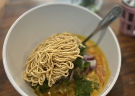 egg noodle with green onion,red shallot,cilantro in thai Northern style yellow curry top with crispy