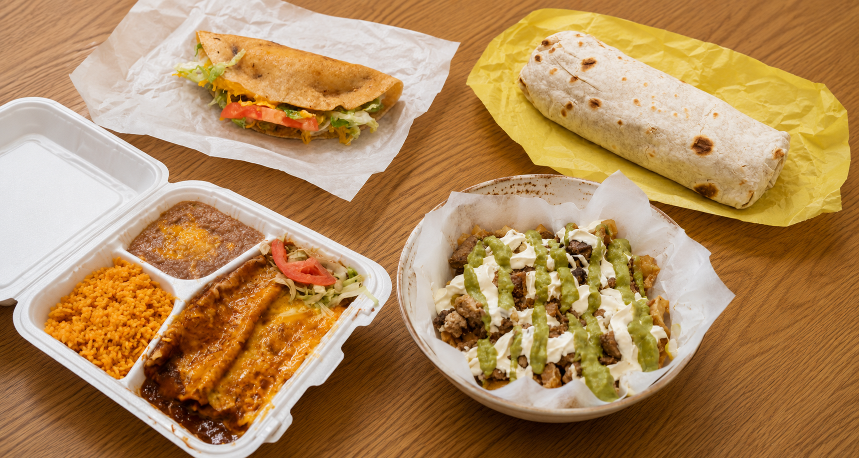 A taco, a burrito in yellow paper, a combination plate and a bowl of deluxe chips on a wooden table