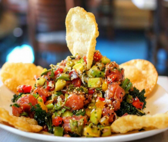 A close-up of ceviche piled on a tostada with avocado and pico de gallo