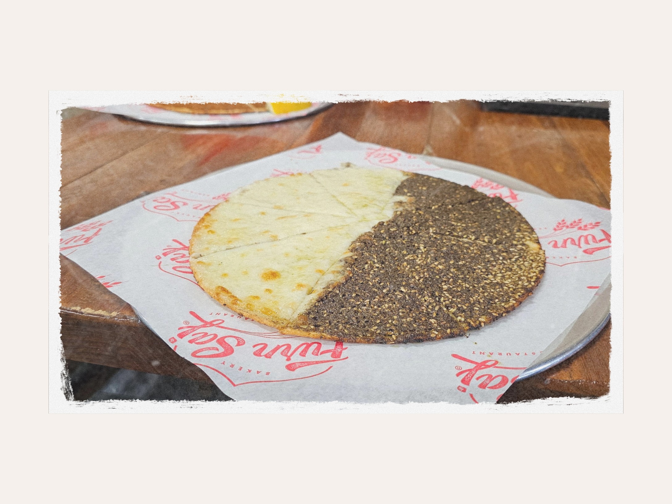 A round flatbread, half zaatar and half cheese, on Furn Saj wax paper