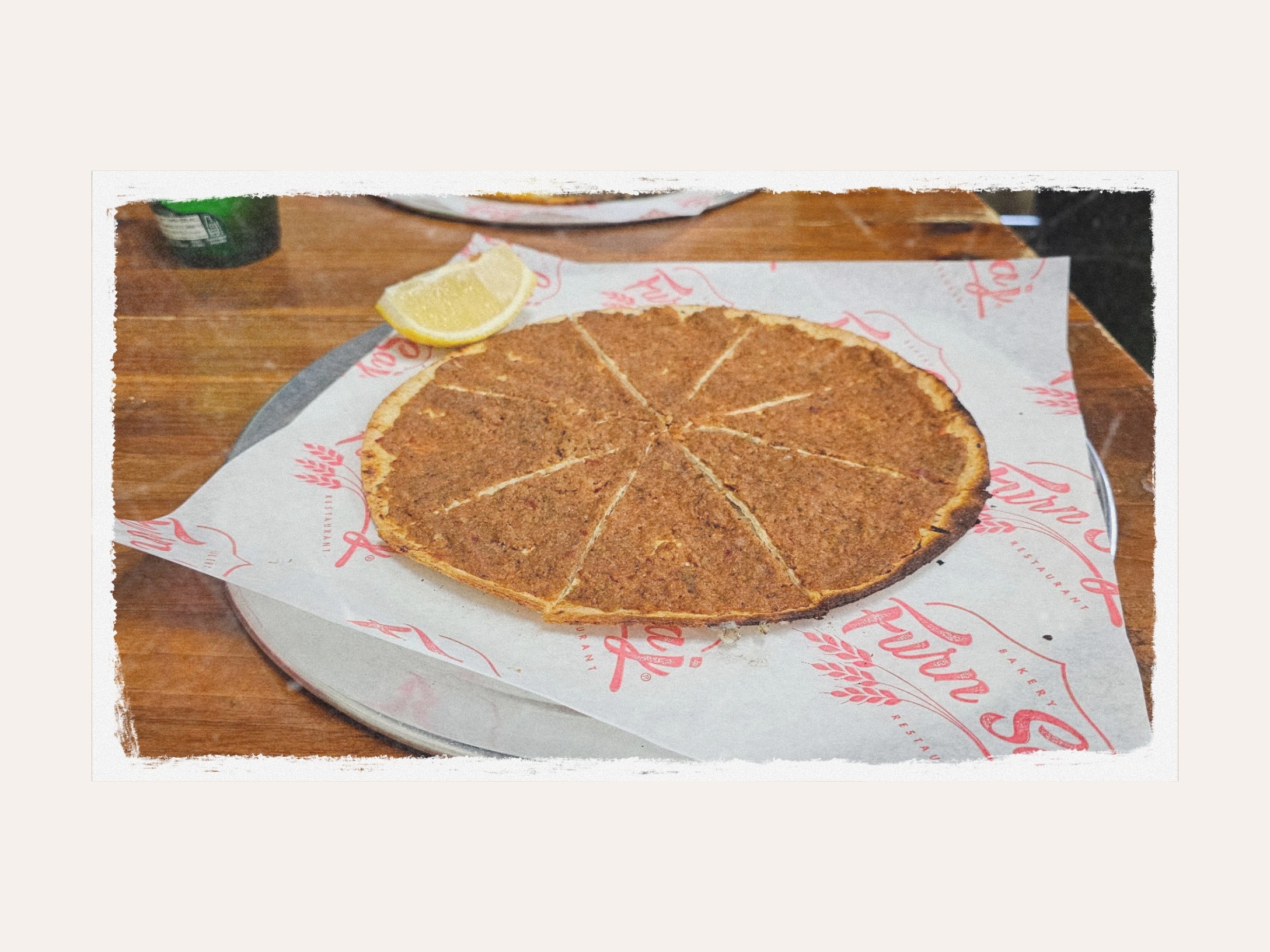 A sliced lahme b'ajine flatbread with a wedge of lemon