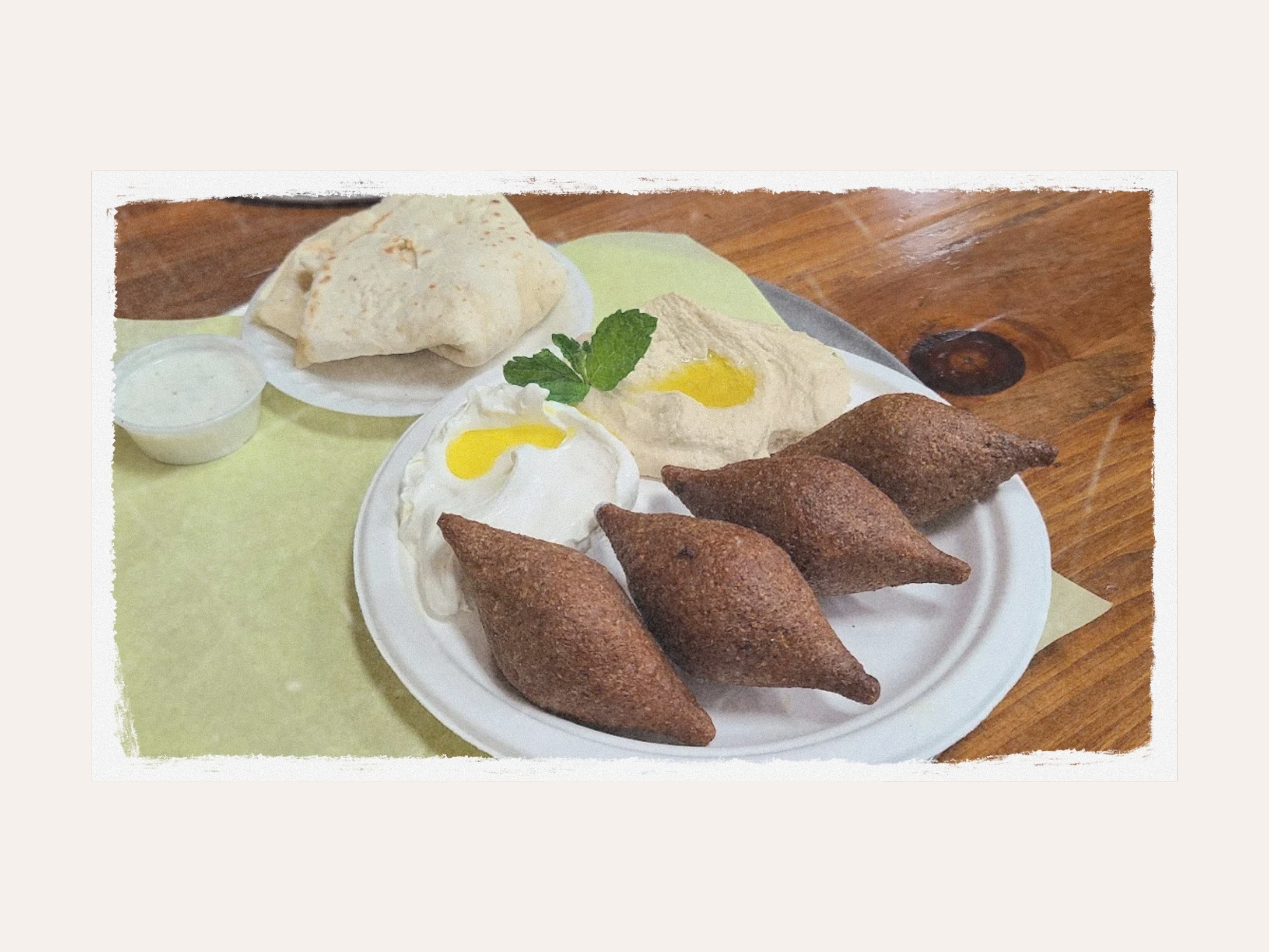 Kibbeh balls with labneh, hummus and pita on a plate