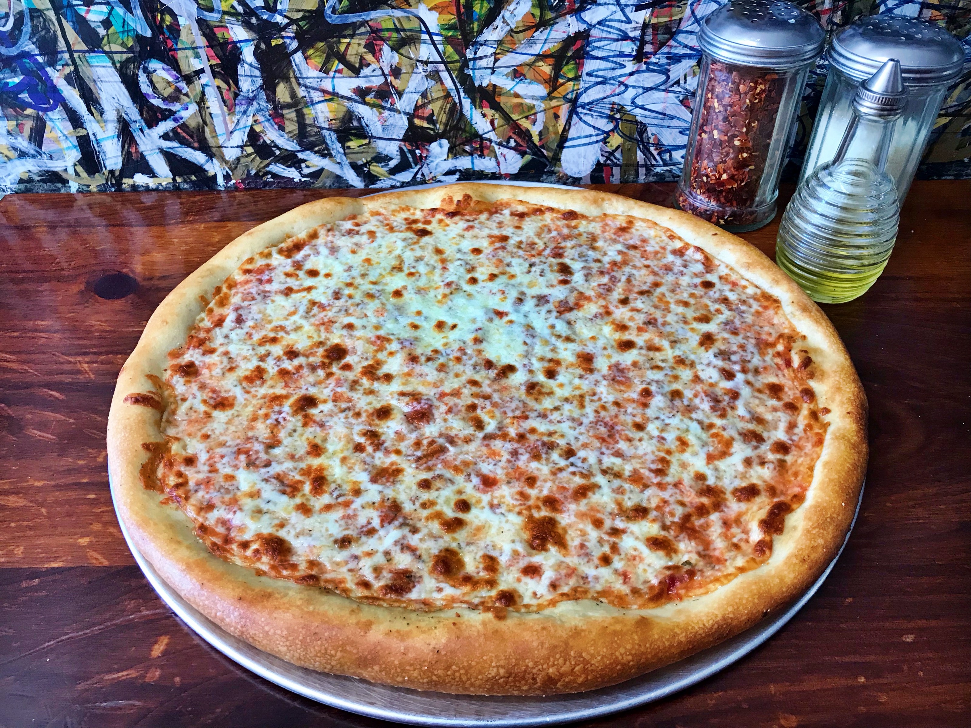 A whole cheese pizza on its tray at Joe Peep's