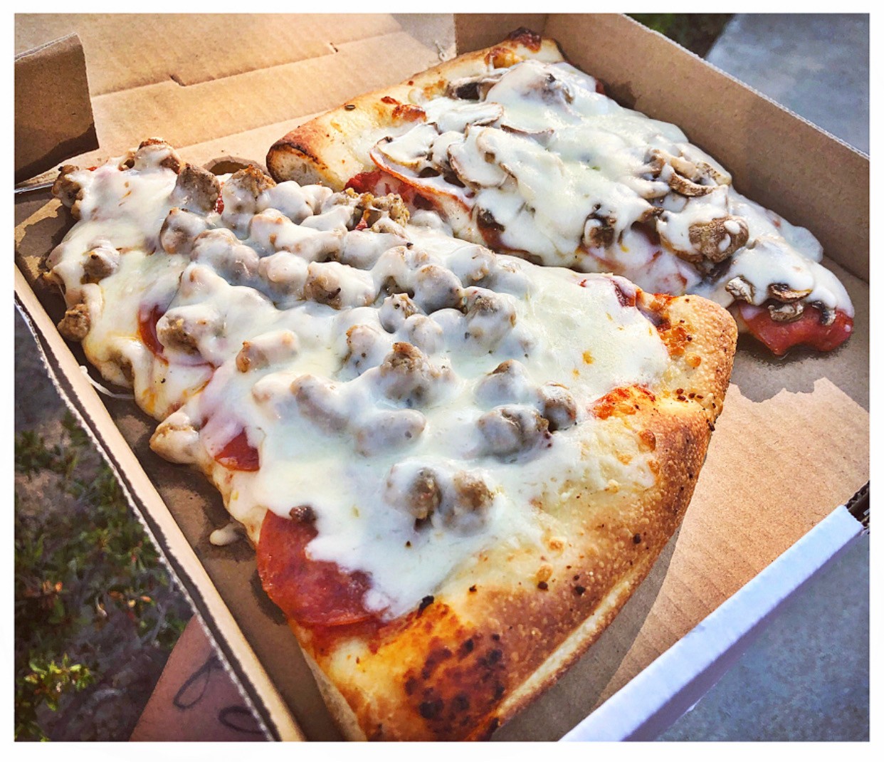 A boxed square slice with toppings
