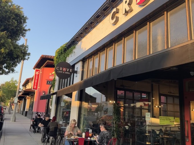 The CRAVE Cafe & Grill storefront at golden hour, with guests at the sidewalk tables