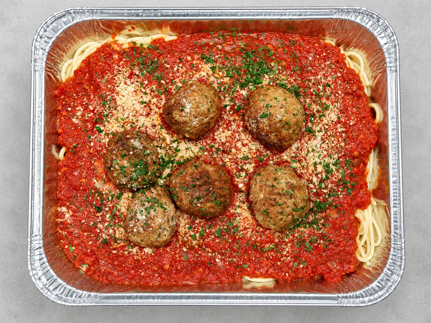 A family tray of baked pasta with melted mozzarella and marinara